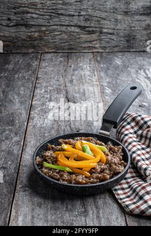 Teriyaki Rinderhack mit Paprika in kleiner Pfanne auf Holz Tabelle Stockfoto