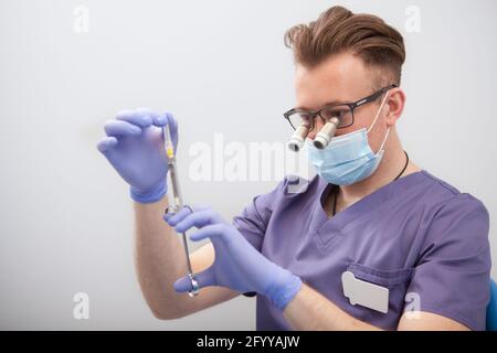 Männlicher Arzt trägt Mikroskopbrille und bereitet Spritze für die Injektion vor Stockfoto