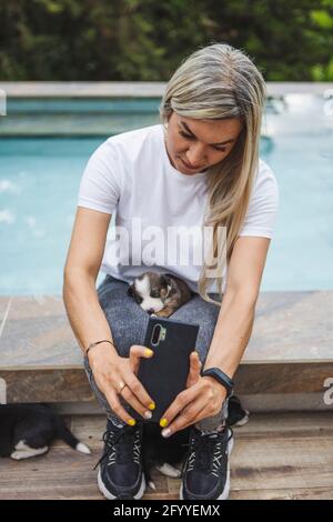 Hündin mit Border Collie Welpe, die Selbstporträt auf dem Handy Während Sie auf der Bank am Pool sitzen Stockfoto