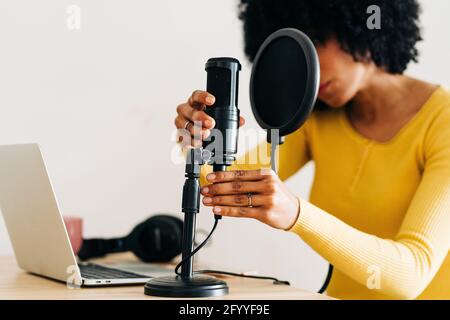 Crop unkenntlich afroamerikanische Musikerin mit dunklen lockigen Haaren Einrichten des Mikrofons vor der Aufnahme des Liedes im Lichtstudio Stockfoto
