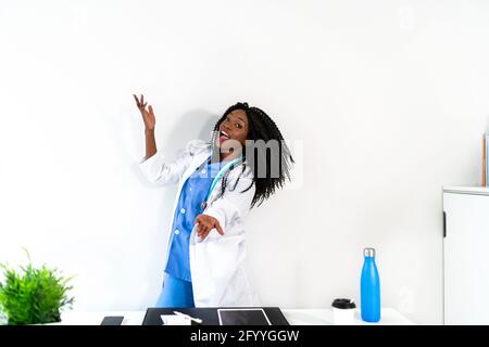 Afroamerikanische Frau in medizinischer Uniform tanzt in der Arztpraxis während der Pause Stockfoto