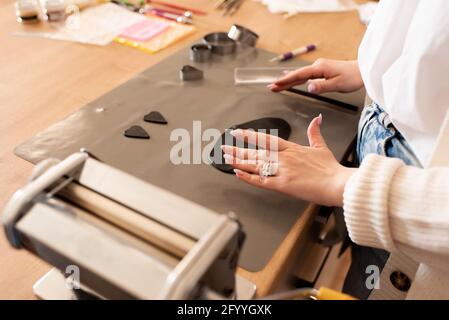 Von oben Ernte anonyme Handwerker bilden Schmuck Details aus schwarzem Ton während der Herstellung von Zubehör in der Werkstatt Stockfoto