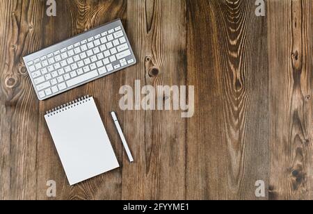 Tastatur, Notizblock und weißer Tischtisch. Konzept - Online-Schulungen, Schulungen, Fernbedienung, Webinare, Seminare, Heimbüro Stockfoto