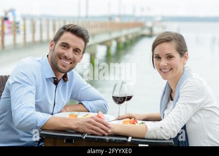 Porträt eines Paares, das auf einer Terrasse am Wasser zu Abend gegessen hat Stockfoto