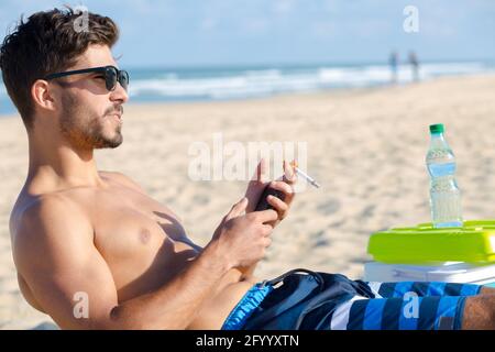 Der Mensch ist das Rauchen am Strand Stockfoto