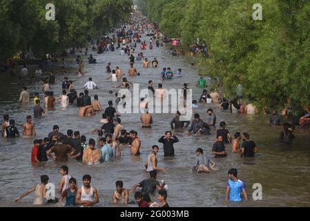 Pakistanische große Anzahl von Menschen, die im Kanalwasser baden, um der Hitze zu entlasten und von dem extrem heißen Wetter etwas Erleichterung zu erhalten, da die Temperatur in Lahore 43 C (111.20 F) erreichte. Nach Angaben des pakistanischen Meteorologischen Departements (PMD) blieb das Wetter in den meisten Teilen des Landes heiß und trocken, die Höchsttemperatur lag in der Provinzhauptstadt bei 43 C (111.20 F) Grad Celsius. Experten prognostizierten, dass die vorherrschenden rauen Wetterbedingungen in der nächsten Woche anhalten werden; zischende Hitze zwang die Menschen, im Haus zu bleiben, was den Verkehr auf ansonsten stark frequentierten Straßen mittags und später verringerte Stockfoto