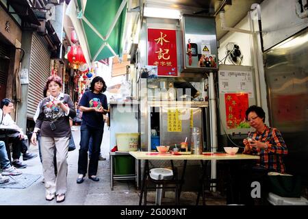 HONGKONG – APR. 19, 2011: Mittags essen die Leute an den Open-Air-Straßenständen, die als Dai Pai Dong im Zentrum von Hongkong bekannt sind. Diese Außenküchen sind Stockfoto