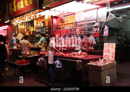 HONGKONG – APR. 14 2011: Metzgerei Verkauf von rohem Fleisch und gekochten Lebensmitteln Verkäufer Verkauf gebratenes Schweinefleisch und Huhn nebeneinander in der Fa Yuen Street m Stockfoto