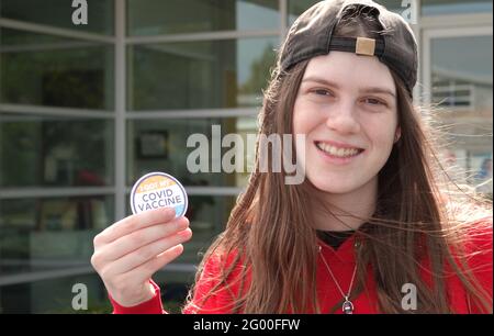 Ein glücklicher, geimpfter Teenager (16 Jahre) Lächelt und zeigt sie „Ich habe meinen Covid-19-Impfstoff“ Aufkleber Stockfoto