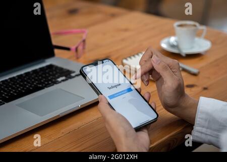 CHIANG MAI, THAILAND - MAI 30 2021: Eine Frau hält das Apple iPhone 11 mit Instagram-Anwendung auf dem Bildschirm im Café. Instagram ist eine App zum Teilen von Fotos Stockfoto