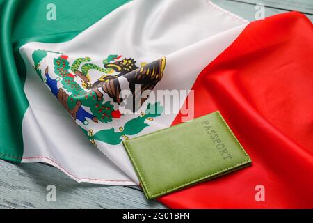 Mexikanische Flagge und Reisepass auf farbigem Holzhintergrund, Nahaufnahme Stockfoto