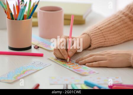 Frau Färbung Lesezeichen am Tisch Stockfoto