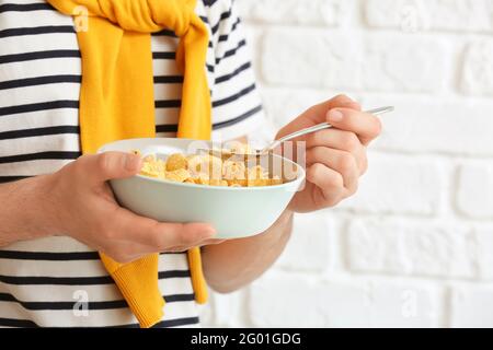 Junger Mann, der auf Backstein Cornflakes isst, Nahaufnahme Stockfoto