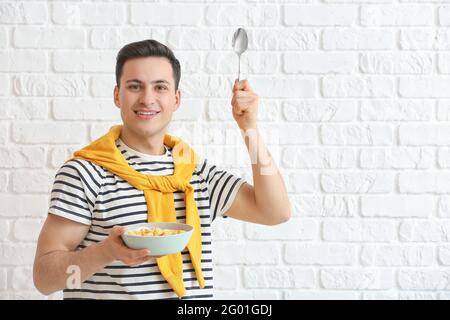Junger Mann und Schüssel mit Cornflakes auf Backstein Hintergrund Stockfoto