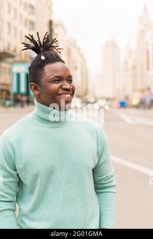 Junger schwarzer Mann mitten in der Stadt, lächelnd. Stockfoto