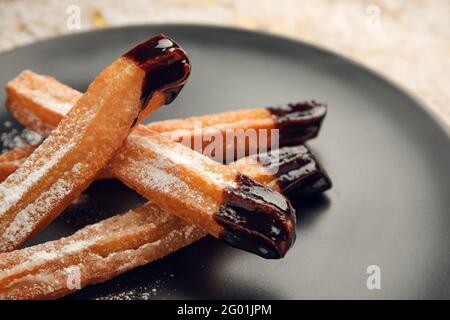 Teller mit leckeren Churros in Schokolade getaucht, Nahaufnahme Stockfoto