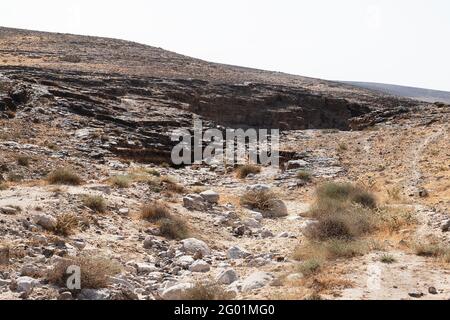 Typische Negev-Wüstenlandschaft südöstlich von Arad in Israel zeigt Eine Schlucht, die aus Furnischichten mit Brocken gebildet wird Kreide im Vordergrund Stockfoto