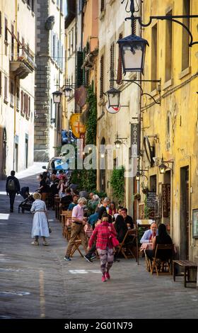 Arezzo, Toskana, Italien, 28. Mai 2021 : viele Bürger und einige Touristen bummeln und essen im Freien auf einer historischen Stadtstraße Stockfoto