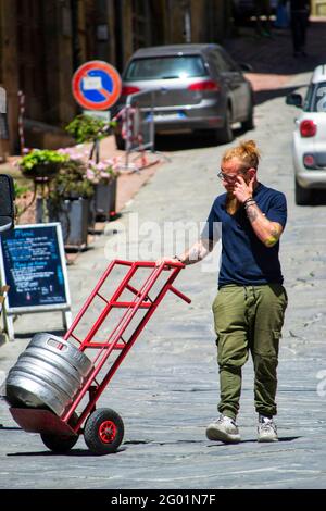 Arezzo, Toskana, Italien, 28. Mai 2021, Junger Mann in seiner Arbeit, der in einer alten Stadtstraße Waren lieferte Stockfoto