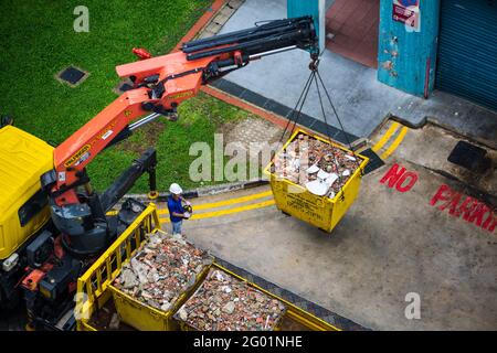 Luftaufnahme eines ein-Mann-Bedieners, der die schweren Industriecontainer hebt und auf die Rückseite des Lastwagens transportiert. Stockfoto