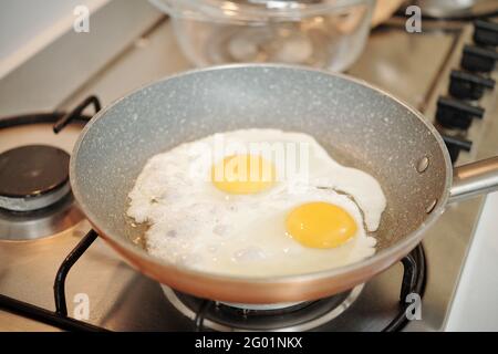 Nahaufnahme der Pfanne mit zwei Spiegeleiern beim Kochen Herd in der Küche Stockfoto