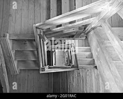 Blick von oben in der Mitte einer hölzernen viereckigen Treppe, schwarz-weißes Bild Stockfoto