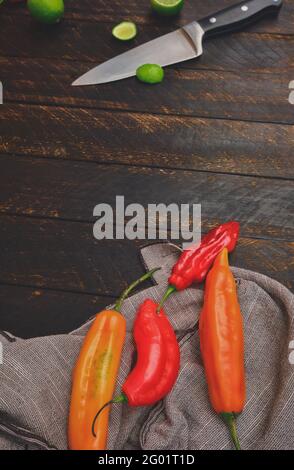 Peruanische Paprika mit anderen Zutaten auf Holztisch und Messer (Limo-Pfeffer, Ecabeche-Pfeffer und Zitrone) Draufsicht. Selektiver Fokus Stockfoto