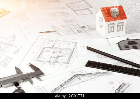 Architekturzeichnungen und kleines Haus. Arbeitsbereich des Architekten mit Bauplänen und Plänen. Stockfoto