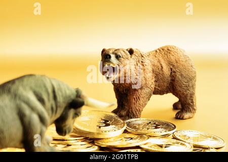 Bär und Stier kämpfen um Bitcoins vor goldenem Hintergrund. Markt-Down-Trend-Konzept. Stockfoto