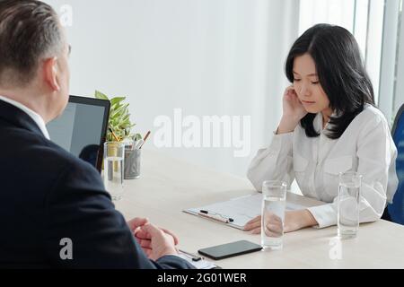 Seriöse junge Geschäftsfrau, die sich ihren lebenslauf ansieht, wenn sie mit ihr spricht HR-Manager am Bürotisch Stockfoto
