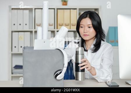 Ernsthafte junge Geschäftsfrau, die ihre Sachen aus dem Kasten nimmt Neuer Schreibtisch Stockfoto