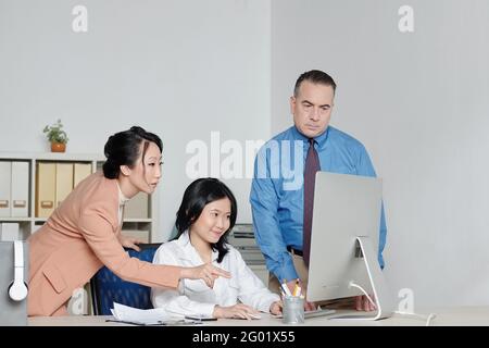 Geschäftsleute helfen neuen Mitarbeitern, Software auf dem Computer zu installieren Neuer Mitarbeiter Stockfoto