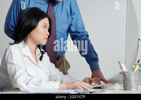 Serious ziemlich junge Geschäftsfrau arbeiten am Computer unter Kontrolle von Ihr Chef Stockfoto
