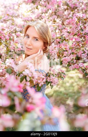 Porträt eines Mädchens in einem blühenden Rosengarten im Sommer. Stockfoto