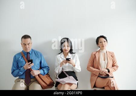 Jobkandidaten sitzen auf Stühlen im Bürokorridor und warten Für ein Interview mit dem Personalmanager Stockfoto