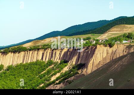 Dorf mit Häusern am Rande von bewaldeten Hügeln Stockfoto