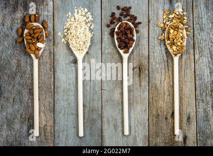 Zutaten für Müsli zum Frühstück, gesunde Ernährung reich an Ballaststoffen: Hafer, Rosinen, Mandeln und Nüsse Stockfoto