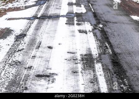 Winterliche Straßenstruktur, Reifenspuren im Schnee und Schlamm Stockfoto