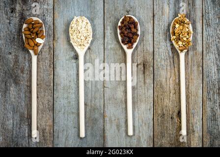 Zutaten für Müsli zum Frühstück, gesunde Ernährung reich an Ballaststoffen: Hafer, Rosinen, Mandeln und Nüsse Stockfoto