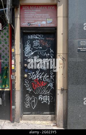 Eine Collage mit Graffiti und Tags an einer Tür in der Steinway Street in Astoria, Queens, New York City. Stockfoto