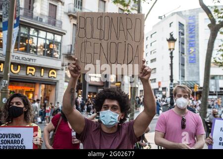 Barcelona, Katalonien, Spanien. Mai 2021. Der Protestierende ist mit einem Transparent mit der Aufschrift Bolsonaro genozidal zu sehen.an dem Tag, der von Demonstrationen in den wichtigsten Städten Brasiliens gegen den brasilianischen Präsidenten Jair Bolsonaro gekennzeichnet ist. Brasilianer in Barcelona haben auf den Ramblas von Barcelona eine Demonstration abgehalten, um sich den Protesten ihres Heimatlandes anzuschließen.Quelle: Thiago Prudencio/DAX/ZUMA Wire/Alamy Live News Stockfoto