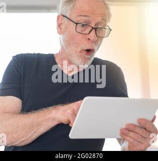 Überrascht reifer Mann Blick auf sein digitales Tablet, Lichteffekt Stockfoto