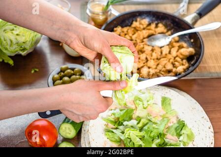 Schnelles Kochen. Hände bereiten Tortilla Wrap mit Huhn und Gemüsesalat, Kebab Gyros Füllung. Stockfoto