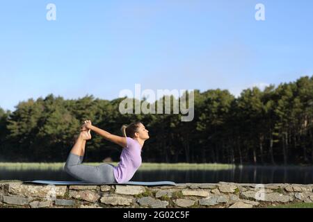 Profil einer Frau, die im Berg Yoga-Pose macht Neben einem See Stockfoto