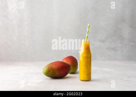 Reife, saftige Mango- und Mango-Smoothies in einem Glas mit Stroh, Platz kopieren Stockfoto
