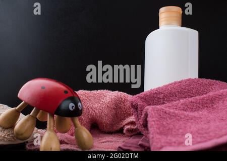 Nahaufnahme von einigen Spa-Sachen wie einem Marienkäfer-förmigen Handmassager, ein paar Handtücher und Creme in einer Flasche Stockfoto