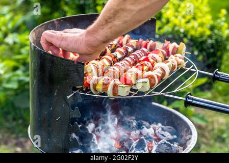 Handgrillen Spieße auf Grill, bbq mit gegrilltem Essen, heiße Wurst, Gemüse und verschiedene Fleisch auf Grillrost über Rauch und Holzkohle Stockfoto