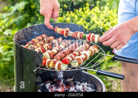 Kochen Sie Grillspieße auf dem Grill mit Hitze und Rauch, Grill im Freien mit bunten Grillgerichten, Nahaufnahme von verschiedenen Fleisch und Gemüse Stockfoto