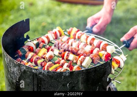 Spieße auf Grill im Garten, Mann, der Schaschlik mit Gemüse und Fleisch zubereitet, Grillgerichte, Party im Freien im Sommergarten Stockfoto