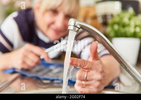 Die Frau, die als Handwerker arbeitet, überprüft die Temperatur des Heißes Wasser am Wasserhahn des Waschbeckens Stockfoto